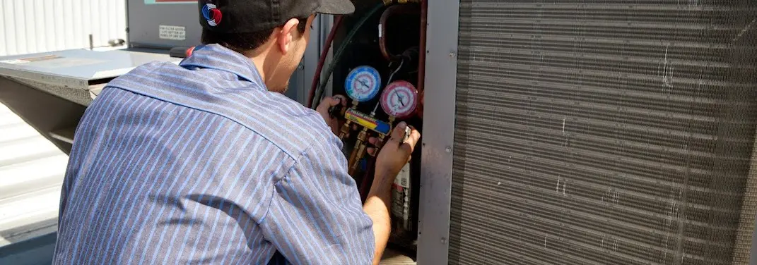 HVAC technician servicing a condenser unit in Wollochet