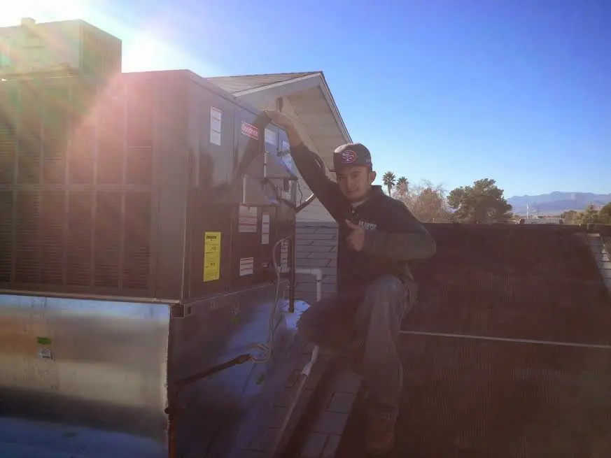 HVAC technician performing Air Duct Repair on a rooftop unit in Wollochet